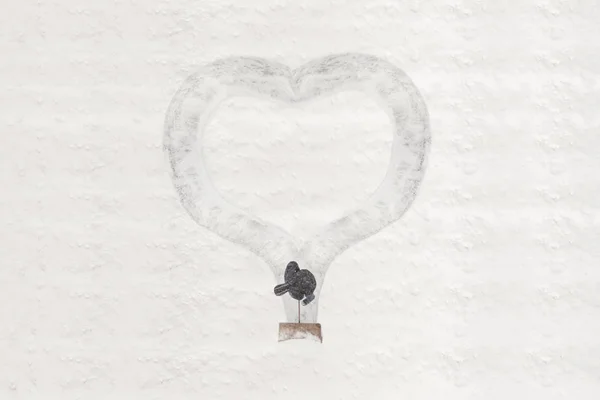 A man cleans the snowy yard and draws by shovel shape of heart on the snow. Concept.Valentine's Day