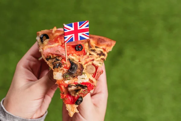 Kousek Pizzy Ženských Rukách Anglickou Vlajkou Formě Párátko Oběd Zelené — Stock fotografie