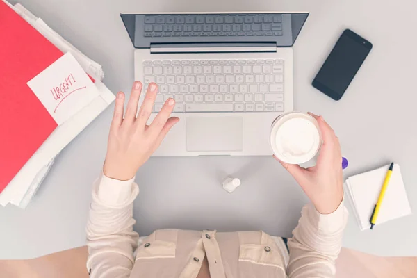 Business woman is painting her nails on the workplace instead of doing the urgent work. Top view