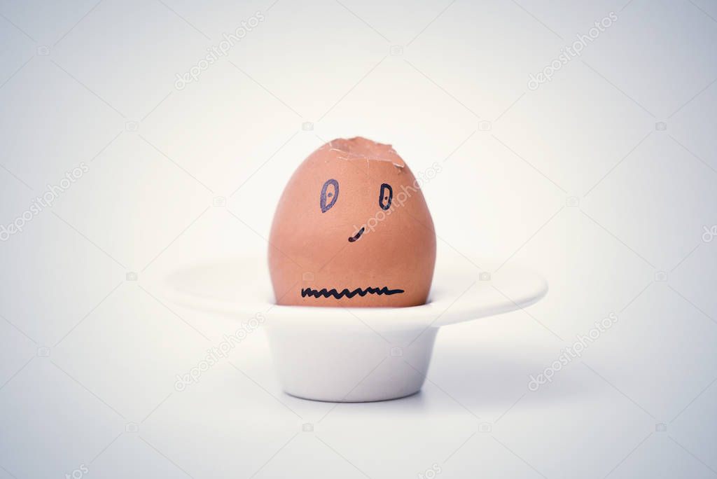 broken brown egg in the form of human head on a stand 