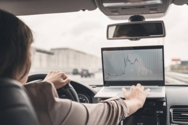 Otobanda yüksek hızda araba sürerken dizüstü bilgisayar kullanarak çalışan iş kadını . 