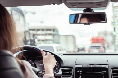 Kadın otobanda araba sürüyor. Arabanın arka koltuğundan bak. 