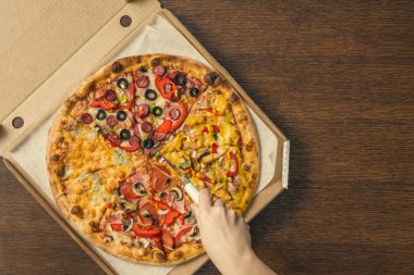Kızın elleri bir kutuda kocaman bir pizza kesmiş. Birpizzada dört pizza