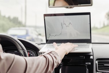 Otobanda yüksek hızda araba sürerken dizüstü bilgisayar kullanarak çalışan iş kadını . 