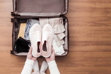 Yeni bir yolculuk için bir bagaj ambalaj kadın elleri üst görünümü. 