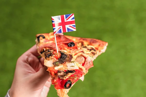 Kousek Pizzy Ženských Rukách Anglickou Vlajkou Formě Párátko Oběd Zelené — Stock fotografie