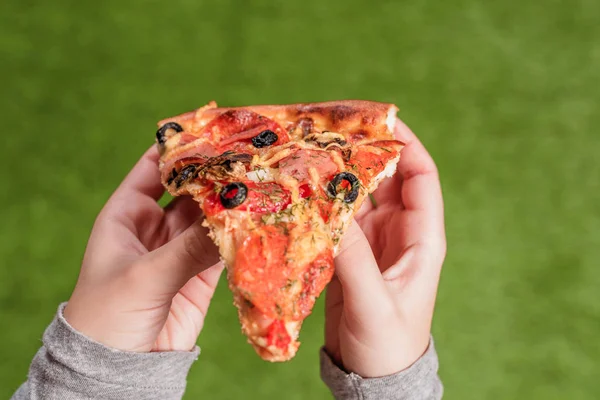 女性の手にピザのスライス 緑の草の上の昼食 — ストック写真
