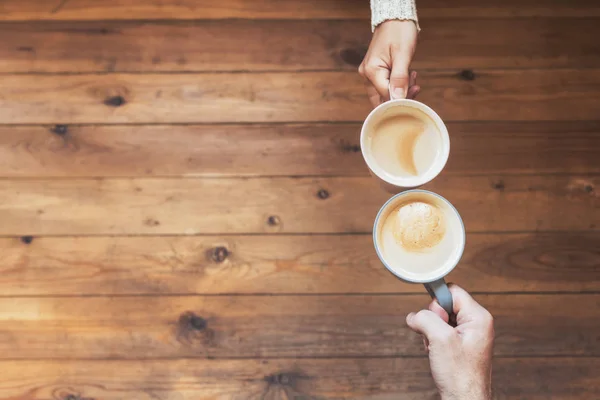 木製のテーブルの背景にコーヒーのカップを持つ男性と女性の手 冬のコンセプト — ストック写真