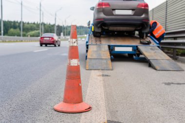 Yoldaki trafik konilerinin dikkatine. Seçici odaklanma. Çekici yolda bozuk bir arabayı çekiyor.