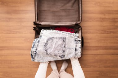 Yeni bir yolculuk için bir bagaj ambalaj kadın elleri üst görünümü. 