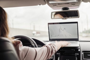 Otobanda yüksek hızda araba sürerken dizüstü bilgisayar kullanarak çalışan iş kadını . 