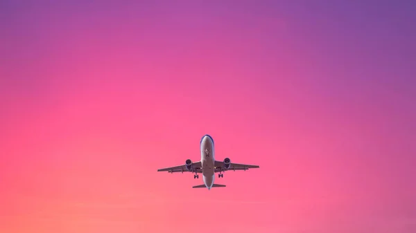パステルカラーの空の背景に着陸飛行機 ピンクとブルーの色の夕日の空 — ストック写真