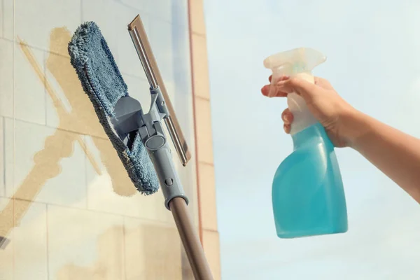 在夏至黄昏时分 女孩可透过喷洒清洁剂及使用拖把海绵擦拭 以清洁阳台的窗户 — 图库照片