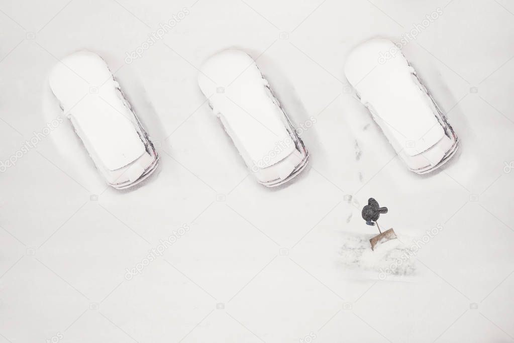 The owner of the car cleans the snow-covered parking space during the snow season. Winter time