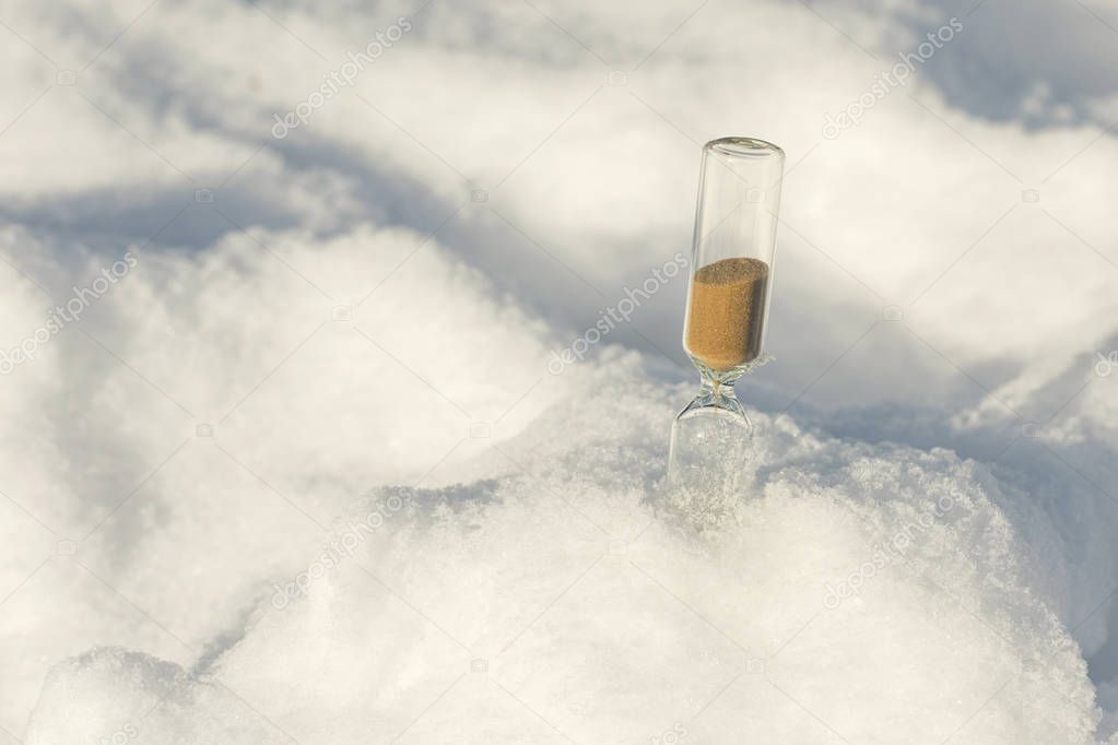 An hourglass in a snowdrift in winter. Symbol of changing of the seasons. Concept