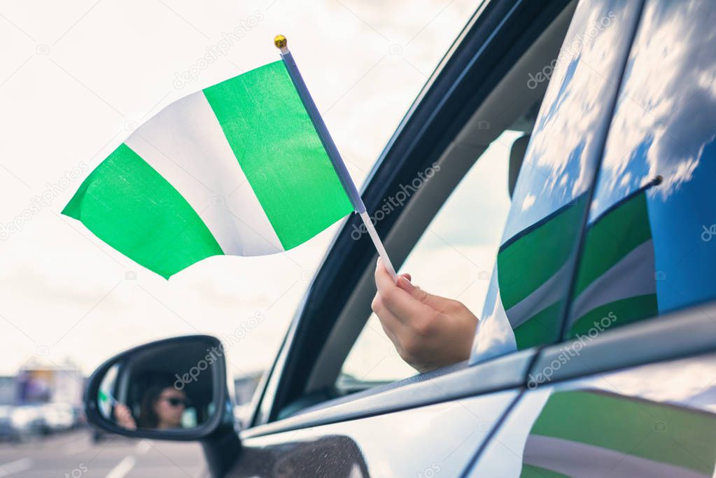 Woman or Girl Holding Nigeria Flag from the open car window