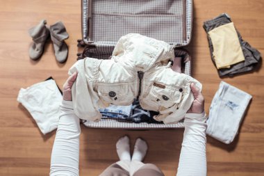 Yeni bir yolculuk için bir bavul (bavul) bir ceket ambalaj kadın elleri üst görünümü. 