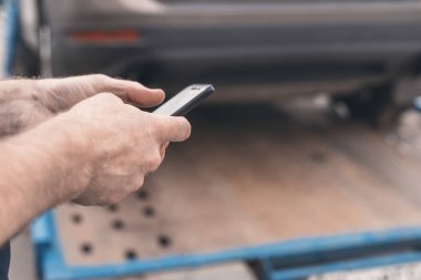 Cep telefonu olan bir adam. Otoyolda bozuk bir arabayı çeken işçili bir çekici. Seçici odaklanma. Kavram