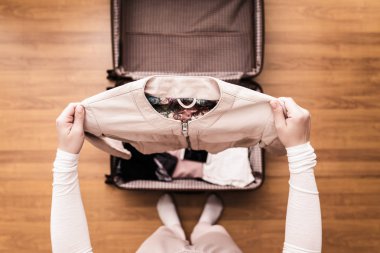 Yeni bir yolculuk için bir bavul (bavul) bir ceket ambalaj kadın elleri üst görünümü. 