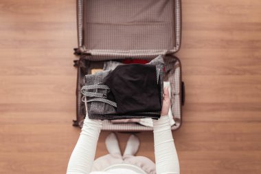 Yeni bir yolculuk için bir bavul (bavul) fitness giyim ambalaj kadın elleri üst görünümü. 