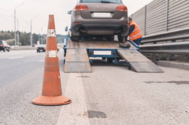 Yoldaki trafik konilerinin dikkatine. Seçici odaklanma. Çekici yolda bozuk bir arabayı çekiyor.