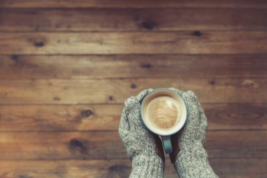Arka planda eldiven ellerde kahve fincanı 