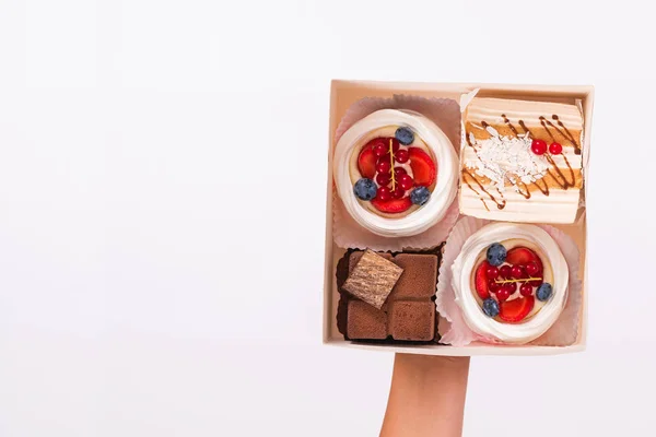 Box with cakes and a cup of coffee in female hands. Top view