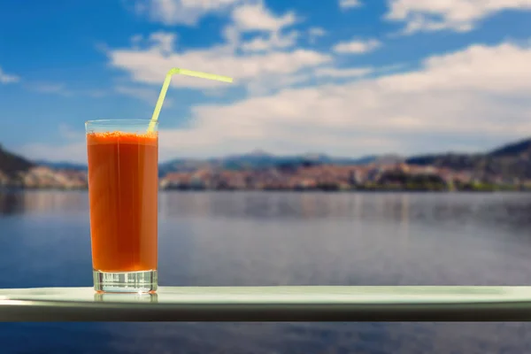 在卡托里亚镇和奥里斯蒂亚斯湖的背景的咖啡馆里 一杯胡萝卜汁和一根稻草 — 图库照片