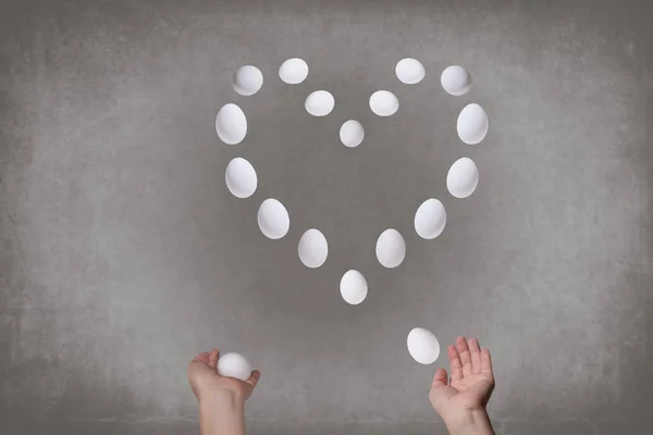 Female hands juggling eggs in the form of Valentine\'s heart . Food concept