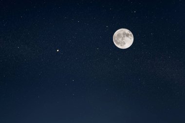 Parlak yıldızlı gece gökyüzünde kocaman bir dolunay.