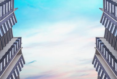 Pastel renklerde bir günbatımı gökyüzü arka plan karşı birbirlerinin karşısında iki simetrik yüksek binalar üzerinde alt görünümü. Metin için alan