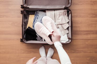 Yeni bir yolculuk için bir bagaj ambalaj kadın elleri üst görünümü. 