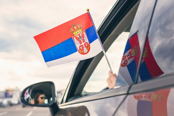 Woman or Girl Holding Serbian Flag from the open car window. Concept