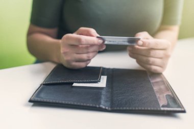 Kafe masasında elinde dosya ve fatura olan kadın eli resmi var. Restoran ziyaretçisi kredi kartıyla ödemeye hazır.