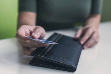 Kafe masasında elinde dosya ve fatura olan kadın eli resmi var. Restoran ziyaretçisi kredi kartıyla ödemeye hazır.