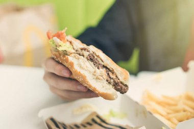  Çocuk duble çizburger yiyor. Yiyecek ve sağlıksız yaşam tarzı kavramı.. 