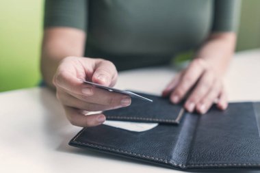 Kafe masasında elinde dosya ve fatura olan kadın eli resmi var. Restoran ziyaretçisi kredi kartıyla ödemeye hazır.