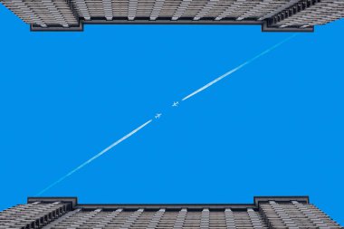 İki bina arasında açık mavi gökyüzünde uçaklar