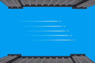 Uçaklar iki bina arasında açık mavi gökyüzünde izler bırakıyor. 