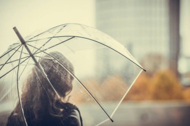 Şehirde şeffaf şemsiyeli yalnız bir kadın var. Sonbahar
