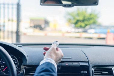 Otomatik bariyeri açmak için uzaktan kumandayı kullanan iş adamı elini kapat. Arabada otur ve park yerinden çık.. 