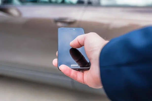 Customer hand holding mobile phone for opening car door. Car sharing service or rental concept.