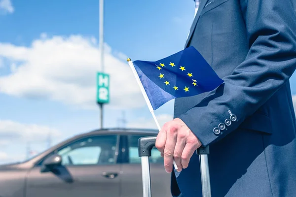 Mann Blauem Anzug Mit Koffer Und Europaflagge Auf Dem Flughafenparkplatz — Stockfoto