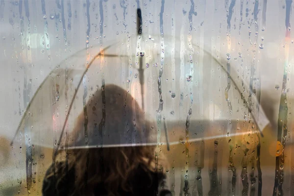 夜の街に雨が降る雨の滴とぬれた窓から透明な傘と女性のシルエット — ストック写真