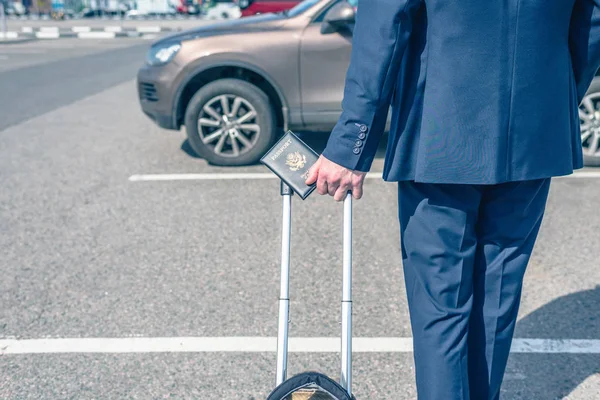 Man pilot in a blue uniform (suit), suitcase and american passport. airport parking rental car. concept