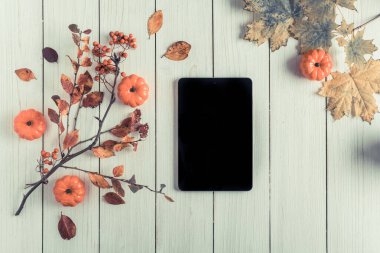 Tablet, yapraklar, beyaz tahta üzerinde küçük balkabakları ve rowan. Geçmişi. Sonbahar, sonbahar konsepti. Düz yerde, üst tarafta. Instagram stili