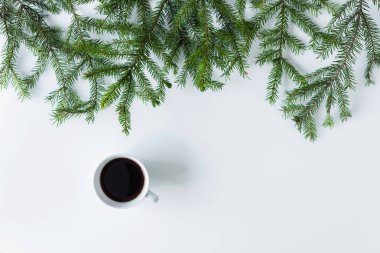 Beyaz bir masanın üzerinde ladin dallı sade kahve fincanı. Noel ve Yeni Yıl konsepti. Kahve sanatı. Düz yatış, üst görünüm. 