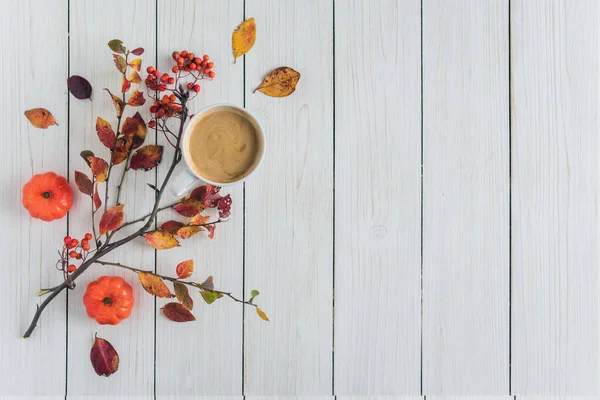 Cup of coffee, leaves, small pumpkins and rowan on white retro wood boards background. Autumn, fall concept. Flat lay, top view.
