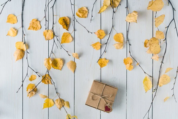 packing gift in a box of kraft paper on white retro wood boards. leaves, birch branches. Thanksgiving. Autumn, fall concept. Flat lay, top view.