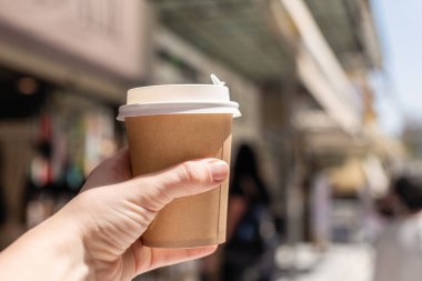 Sokakta elinde bir fincan kahveyle dolaşan bir kız. Kahveni götür. Seçici odak 
